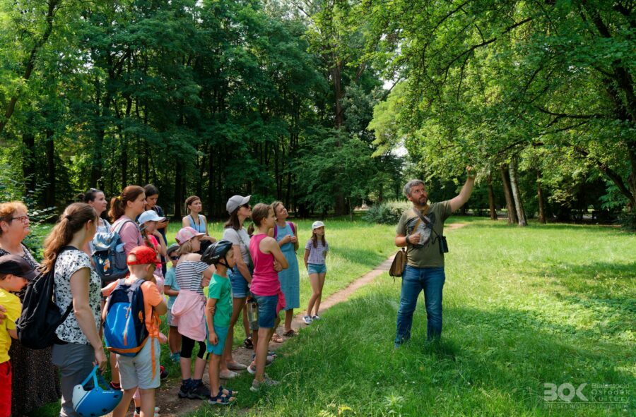 Paweł Średziński w lesie pokazuje coś uczestnikom spaceru