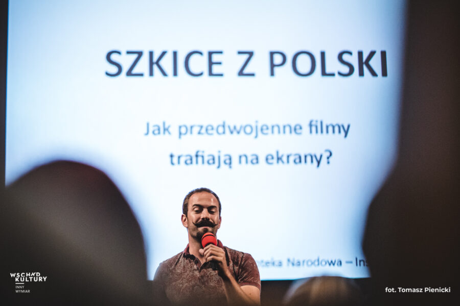 Prelegent stoi przed wyświetlaną na ekranie planszą z napisem "Szkice z Polski. Jak przedwojenne filmy trafiają na ekrany?"